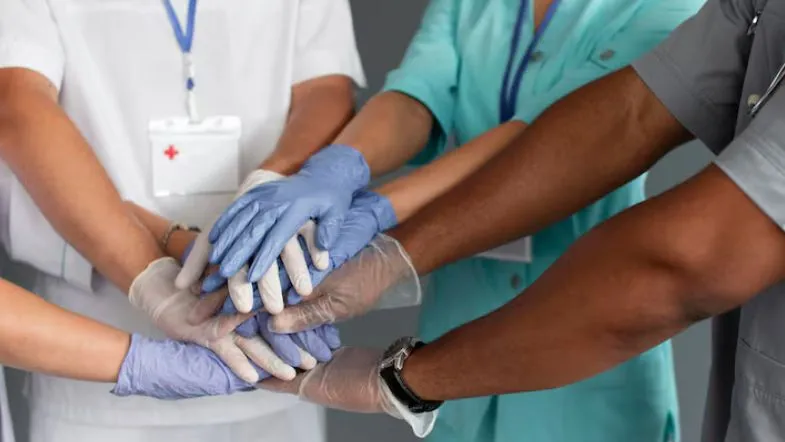 Como a saúde mental vai redefinir a gestão hospitalar nos próximos anos 9 Mãos unidas de profissionais de saúde simbolizando cooperação e união nas práticas de gestão hospitalar.