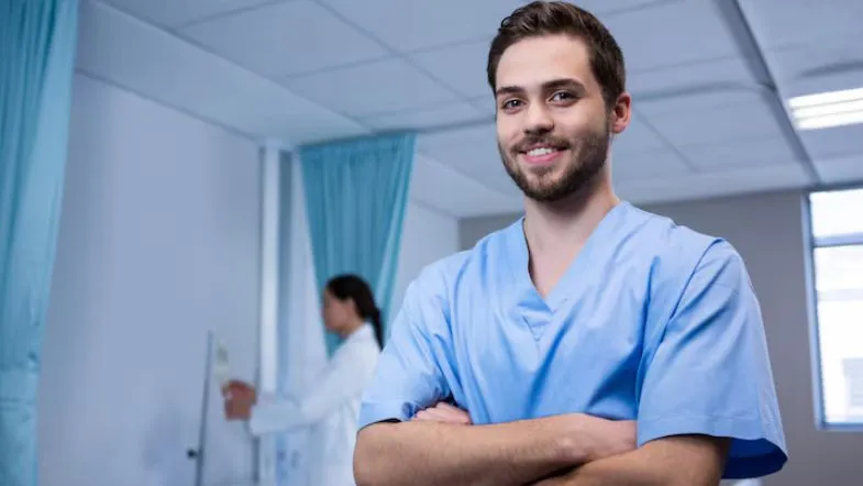 Enfermeiro sorridente com uniforme azul em ambiente hospitalar, representando a atuação na saúde do homem durante o Novembro Azul.