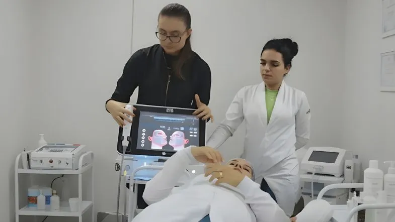 Instrutora e estudante de estética utilizando equipamento de ultrassom microfocado durante prática supervisionada.