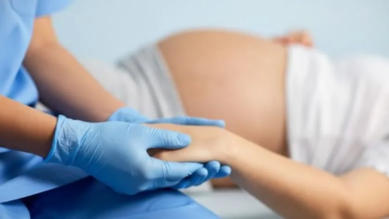 Obstetrícia na prática: como a pós-graduação presencial forma especialistas 6 Profissional de saúde segurando a mão de uma gestante durante assistência obstétrica.