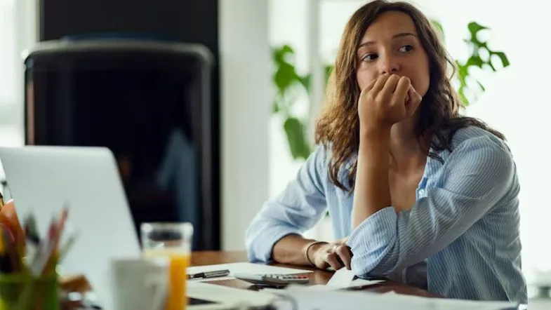 Profissional preocupada no ambiente de trabalho, representando sinais de ansiedade e impactos na saúde mental.