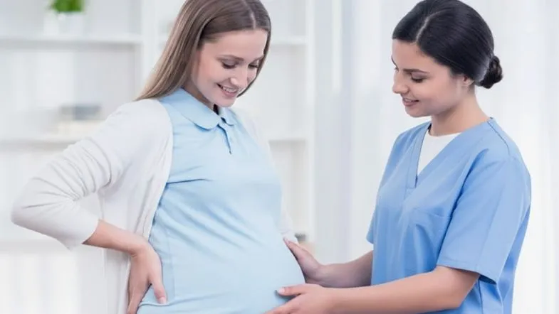 Enfermeira obstetra examinando gestante durante consulta pré-natal em ambiente ambulatorial.