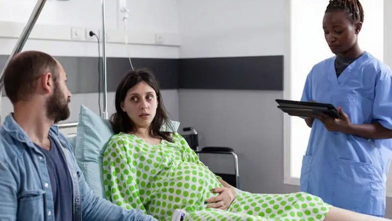 Profissionais da enfermagem obstétrica prestando assistência a gestante em trabalho de parto, ao lado do parceiro, com abordagem humanizada.