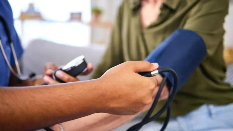 Profissional de saúde aferindo pressão arterial de um paciente, destacando cuidados essenciais para manter a saúde em dia.