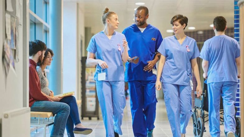 Gestão Hospitalar em 2025: como reduzir custos sem perder qualidade 7 Profissionais de saúde caminhando em hospital moderno simbolizando trabalho em equipe e eficiência na gestão hospitalar.