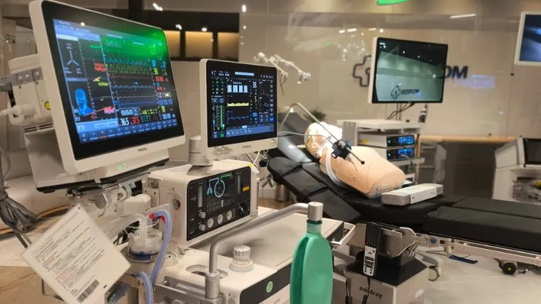 Leito de simulação realística com manequim e equipamentos hospitalares avançados em laboratório preparado para treinamento de emergências.