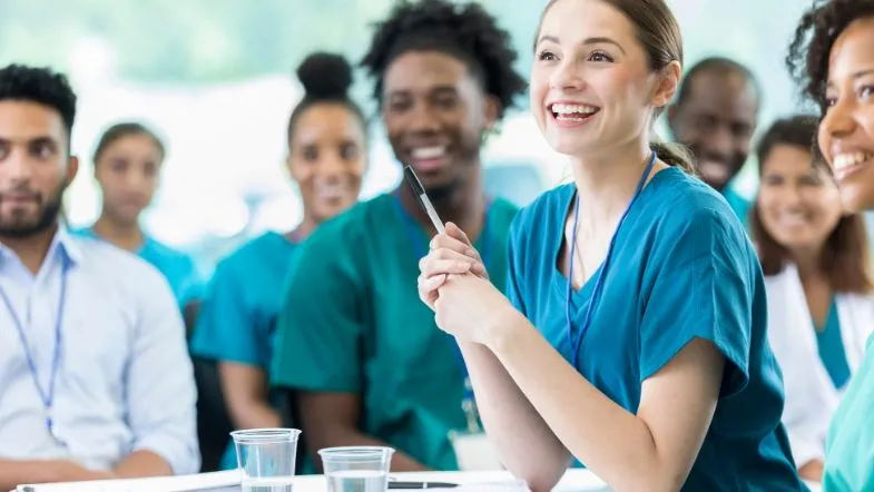 Grupo de profissionais de enfermagem em ambiente de capacitação, participando de aula ou treinamento.