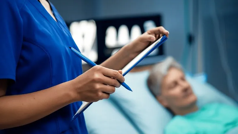 Enfermeira utilizando tablet à beira do leito para monitorar indicadores de segurança do paciente.