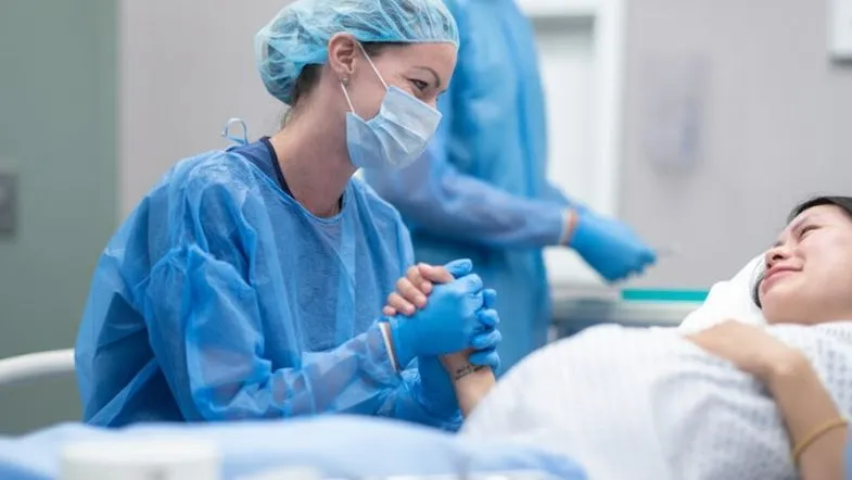 Enfermeira obstetra oferecendo apoio emocional à parturiente durante o trabalho de parto.