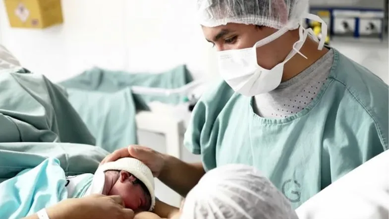 Obstetrícia na prática: como a pós-graduação presencial forma especialistas 9 Enfermeiro especializado em obstetrícia acolhendo recém-nascido no colo logo após o parto.