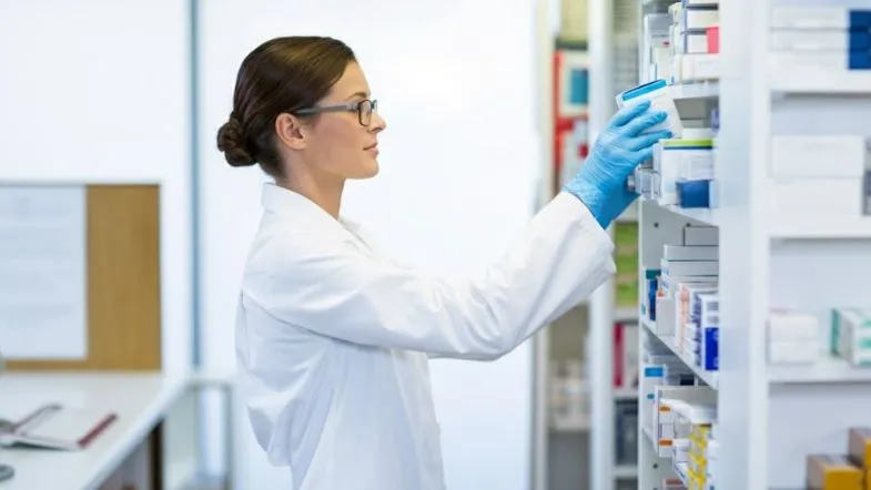 Farmácia Clínica em 2025: a regulamentação que ampliou o protagonismo do farmacêutico 9 Farmacêutica selecionando medicamentos em prateleira de farmácia hospitalar.