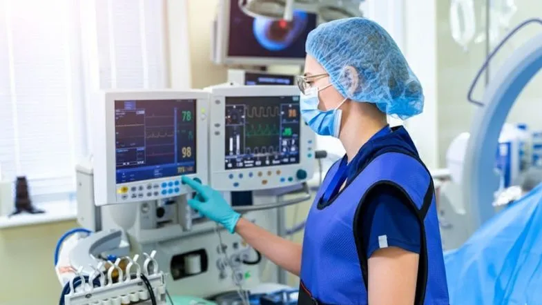 O futuro da emergência hospitalar: o que muda em 2026 e qual formação será obrigatória 6 Profissional da saúde manuseando monitor cardíaco em sala de emergência.