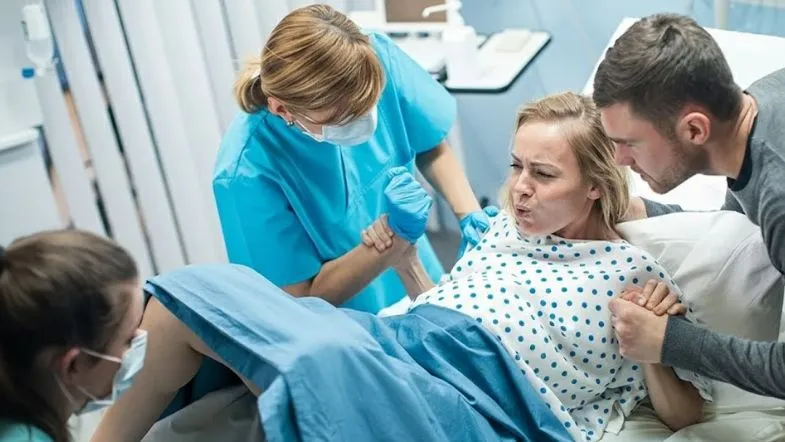 Gestante em trabalho de parto recebendo assistência de enfermeira e apoio do acompanhante, demonstrando a importância da obstetrícia humanizada no parto. 