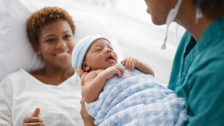 Parto baseado em evidências: o que muda para a enfermagem obstétrica em 2026 9 Enfermeira obstétrica apoiando gestante em leito hospitalar, reforçando cuidado humanizado e segura assistência ao parto.