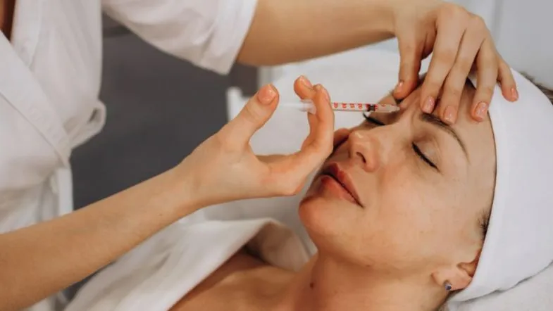 Faculdade ITH oferece aula prática de Harmonização Facial em Goiânia 9 Profissional aplica injeção estética na região da testa de paciente modelo, em aula prática de harmonização facial.