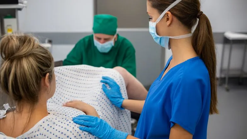 Equipe de saúde acompanhando o período expulsivo de uma gestante em posição semi-sentada.