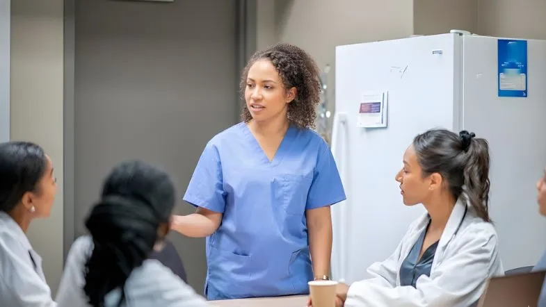 Enfermeira coordenando reunião com equipe de enfermagem, demonstrando comunicação assertiva e liderança na prática clínica.