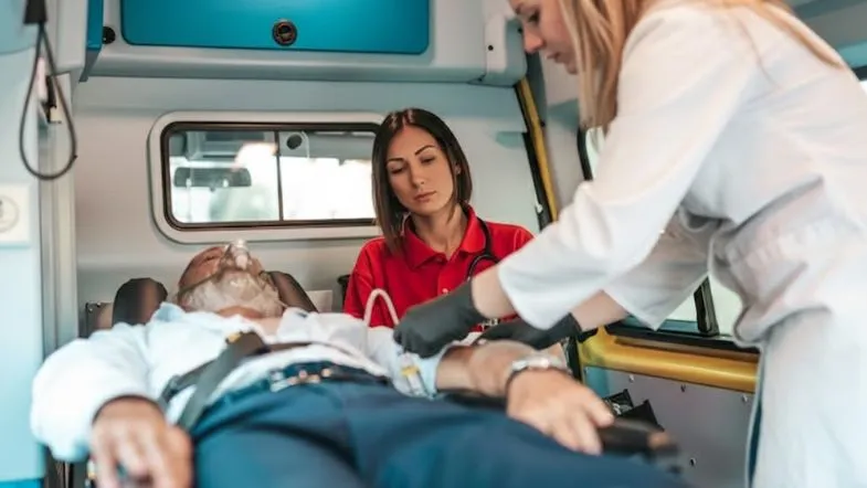 Enfermeiros prestando atendimento de urgência dentro de uma ambulância, ilustrando a prática clínica em situações críticas.