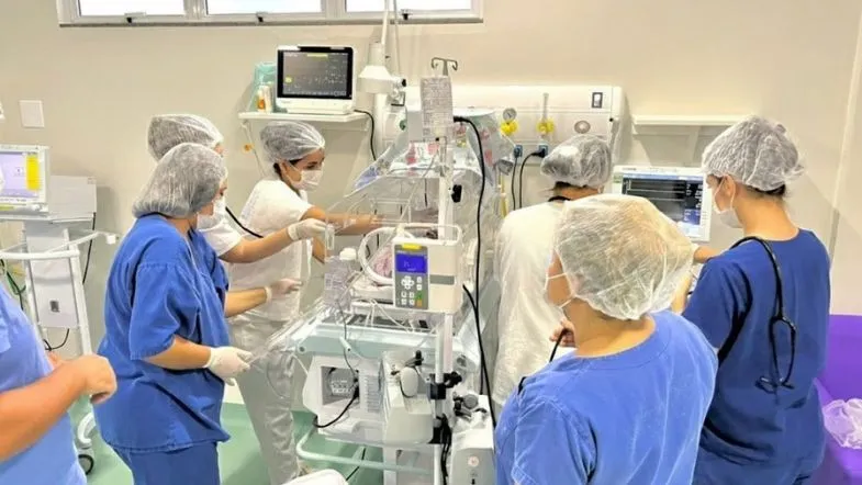 Pós-graduação em UTI Neonatal e Pediátrica: como alavancar sua carreira na saúde em 2026 7 Equipe de profissionais de saúde realizando atendimento conjunto em um recém-nascido dentro de uma incubadora em UTI Neonatal e Pediátrica.