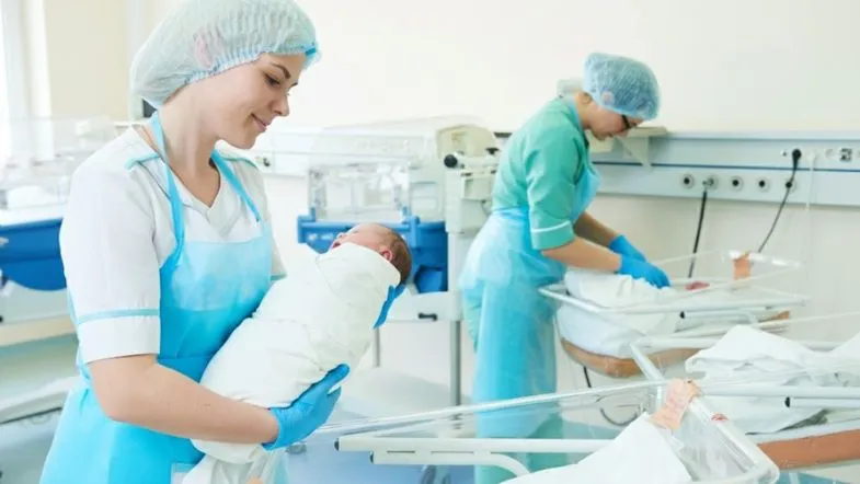 Enfermeiras obstétricas em maternidade cuidando de recém-nascidos no alojamento conjunto, evidenciando a atuação assistencial especializada.