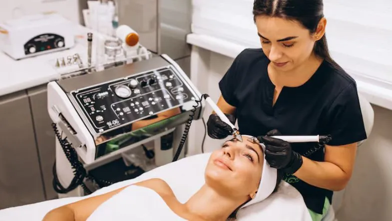 Profissional de estética executando procedimento facial com protocolo clínico e equipamento tecnológico, alinhado às exigências do mercado em 2026.