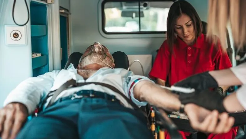 Paciente sendo monitorado em ambulância por profissionais de saúde, ilustrando atendimento crítico em contexto de urgência.